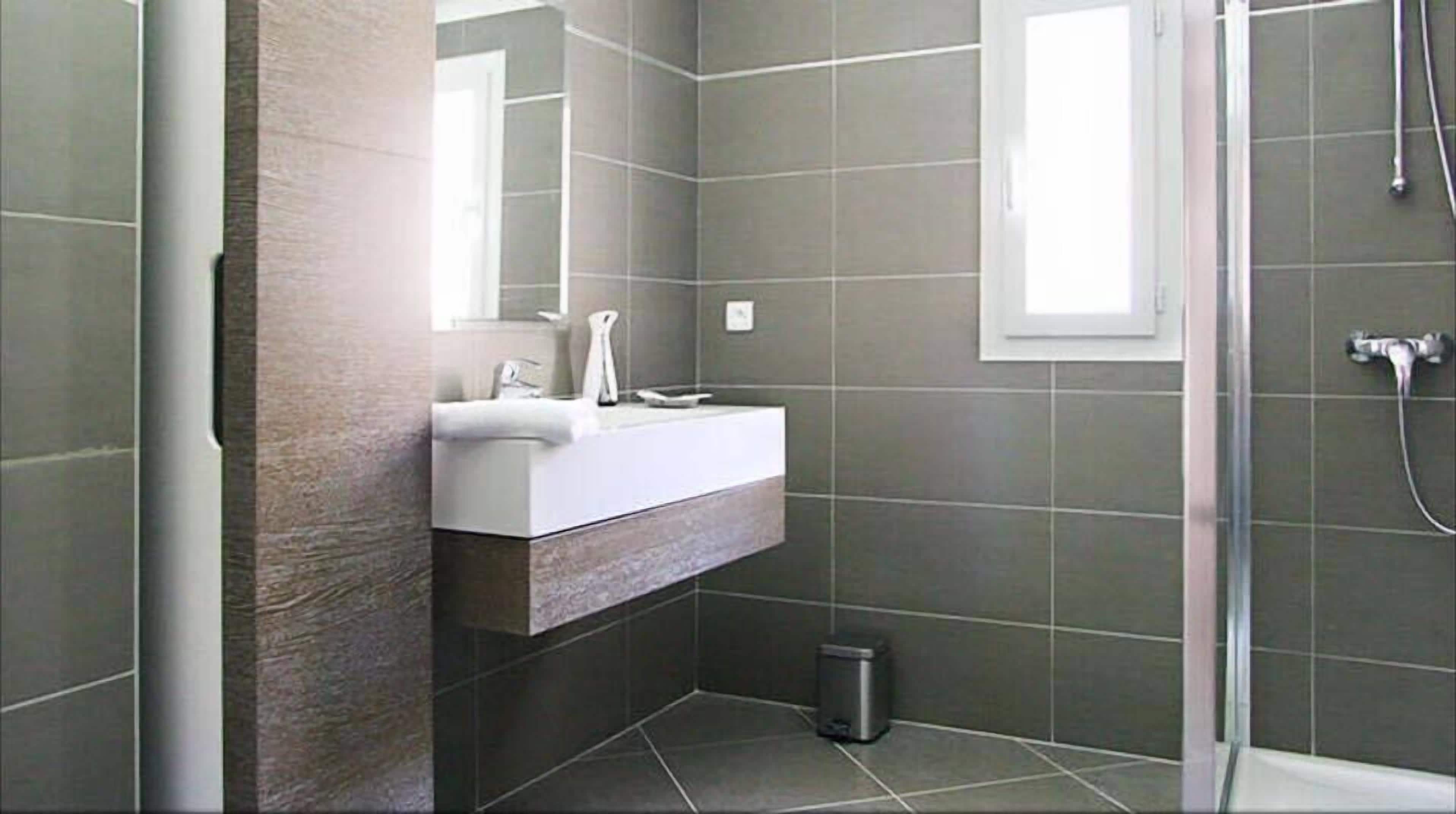 A bathroom with a white sink, a mirror, and a shower area.