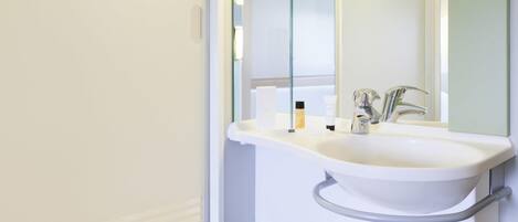 Un baño con un lavamanos blanco, un espejo y una toalla sobre un estante.