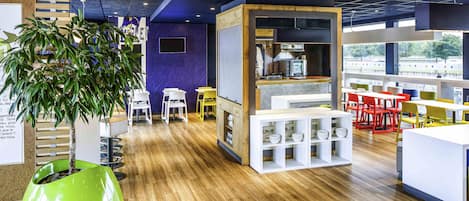 A modern interior with a kitchen area, seating arrangements, and a large green planter.
