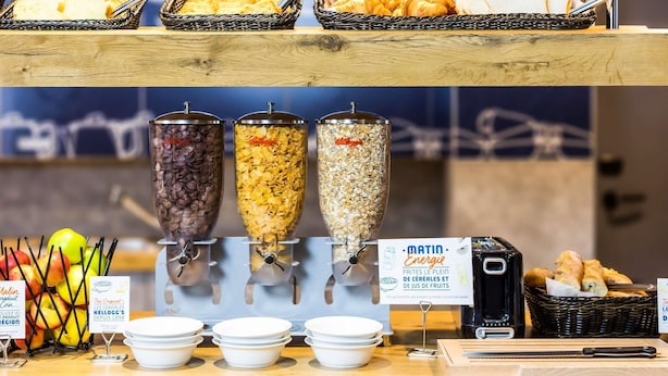 A breakfast buffet with cereal and fruit options, a coffee machine, and a sign promoting energy breakfast. - ibis budget Edinburgh Park (Edinburgh)