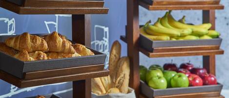 Un bufé de desayuno con pasteles, frutas y pan.