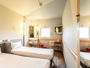 A hotel room with two beds, a desk, a mirror, a TV, and a window. - ibis budget Bourges (Le Subdray)