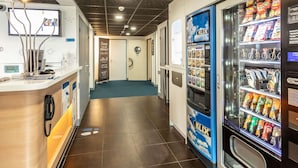 A reception area with a counter, a K-LIX vending machine, and a door labeled "Envie." - ibis budget Bourges (Le Subdray)