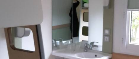 Uma casa de banho compacta com lavatório, espelho e janela.