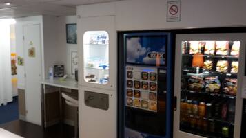 A vending machine with snacks and drinks, a no smoking sign, and a window with a view of the outside.