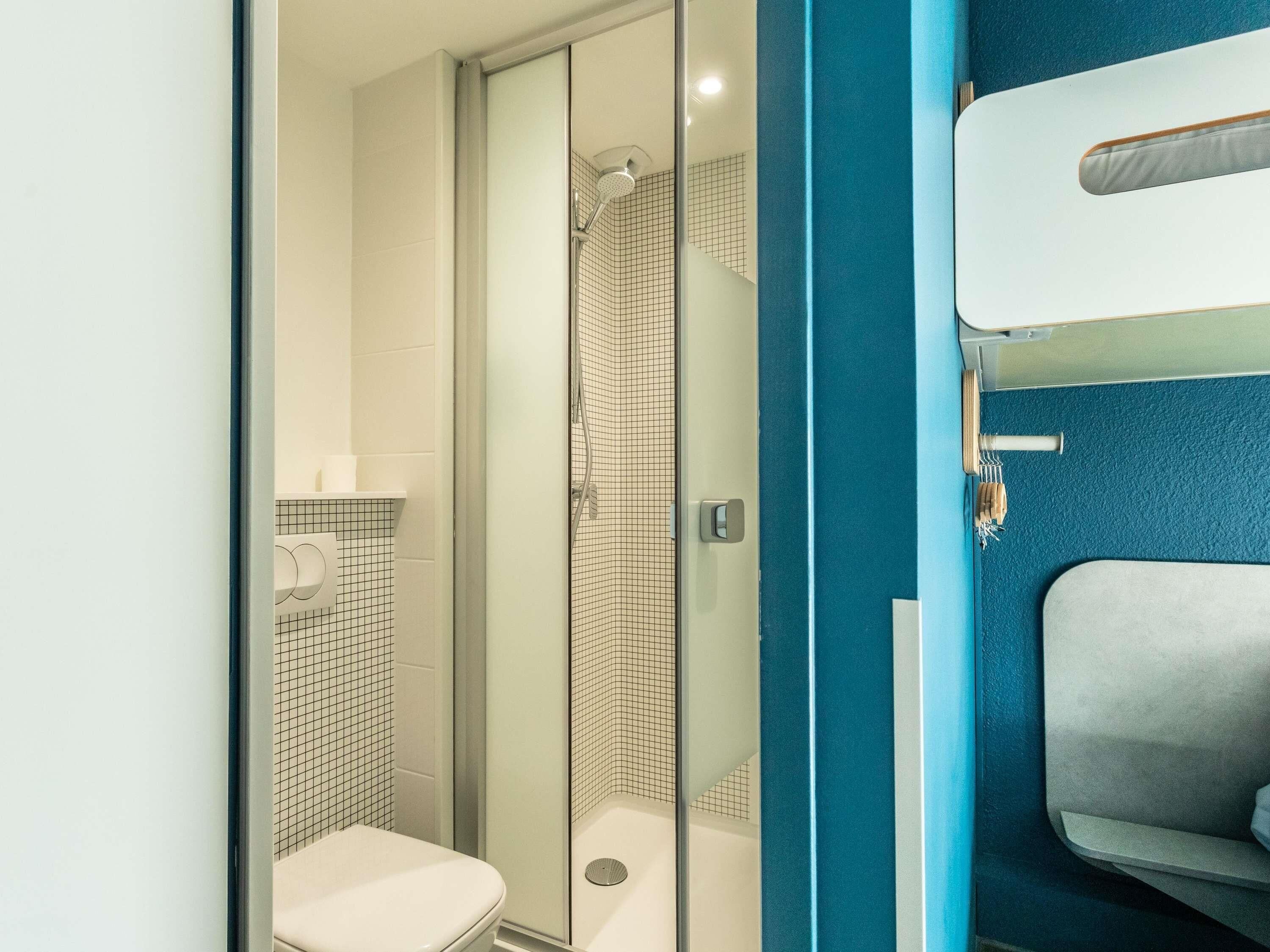 Un baño moderno con ducha envuelta en vidrio, inodoro y lavamanos con toallero.