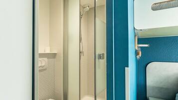Un baño moderno con ducha envuelta en vidrio, inodoro y lavamanos con toallero.