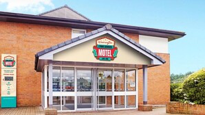Un motel avec une enseigne bien visible, de grandes fenêtres et une façade en briques.