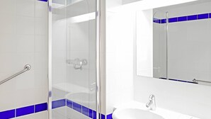 Une salle de bain moderne avec une douche à parois de verre, un lavabo blanc et des murs recouverts de carreaux bleus.