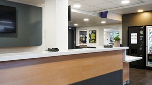 Un comptoir d’accueil équipé d’un téléviseur à écran plat, d’une plante et d’un distributeur automatique.