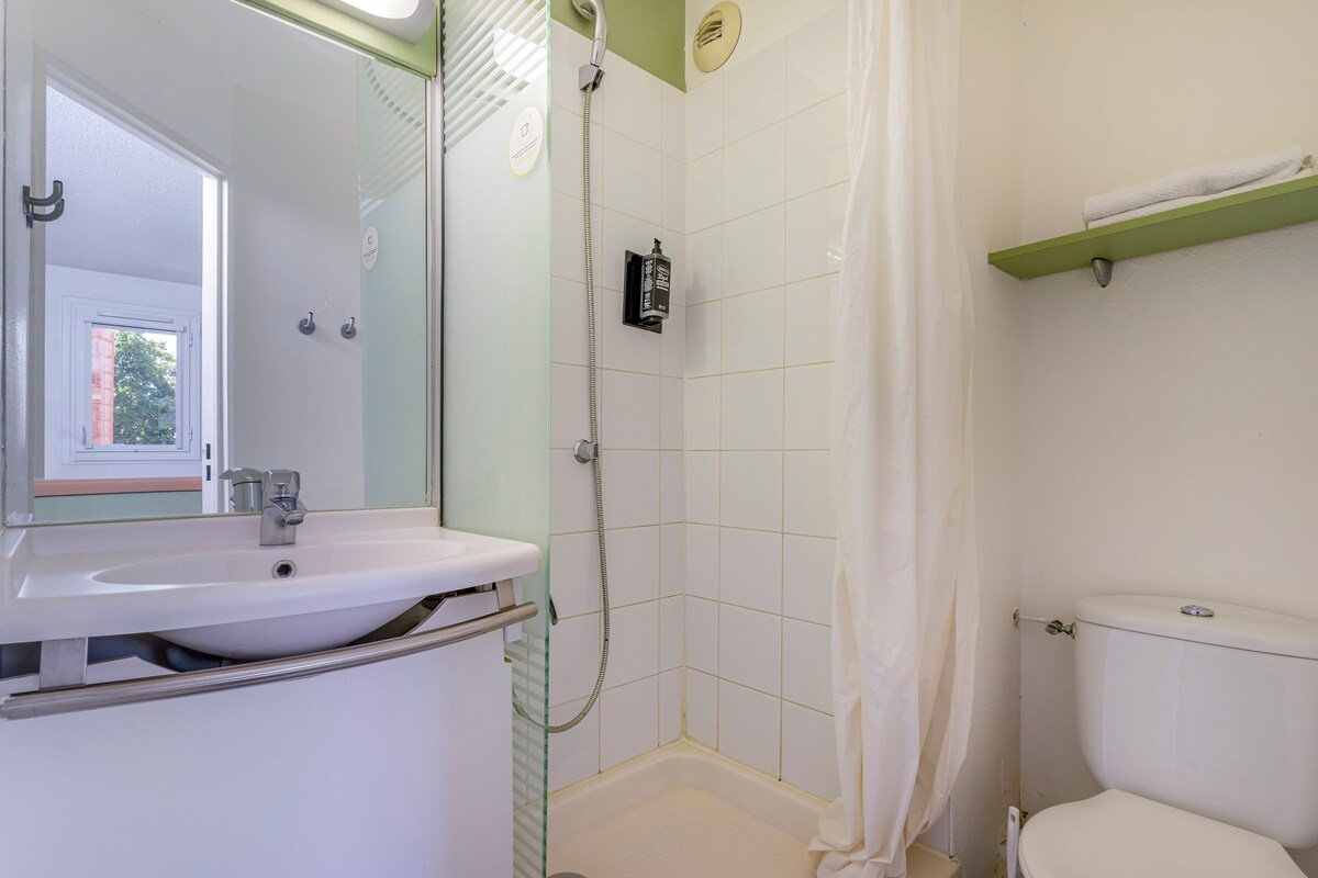 Ein Badezimmer mit einem weißen Waschbecken, einer Dusche und einer Toilette.