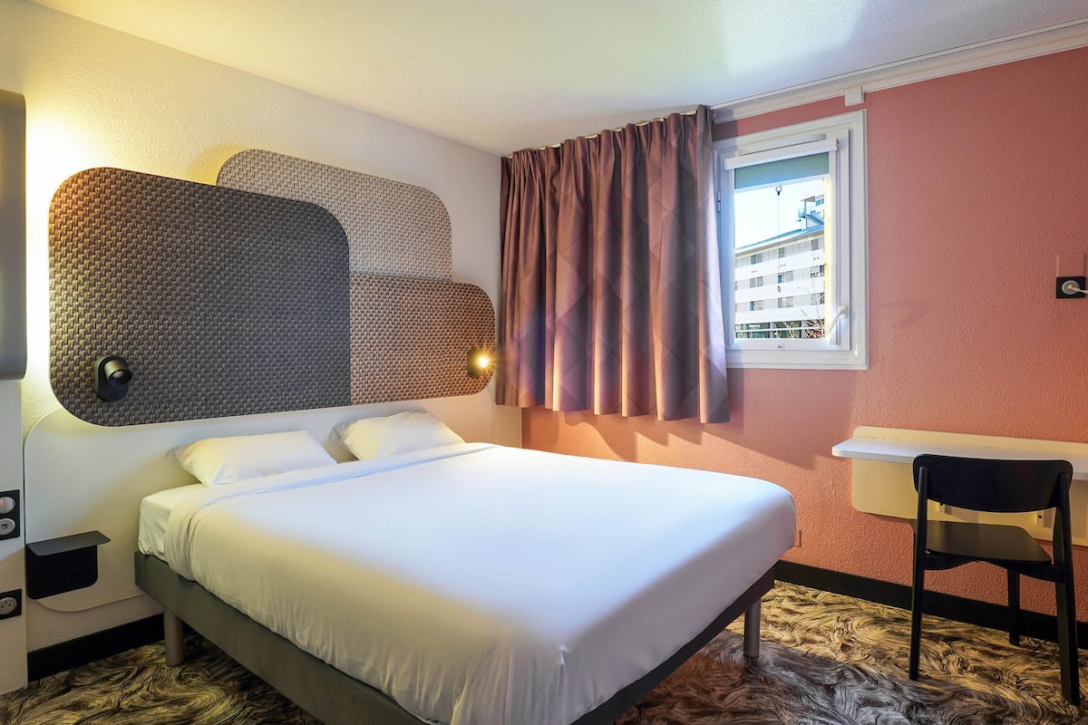 Une chambre d’hôtel avec un lit, un bureau et une chaise.