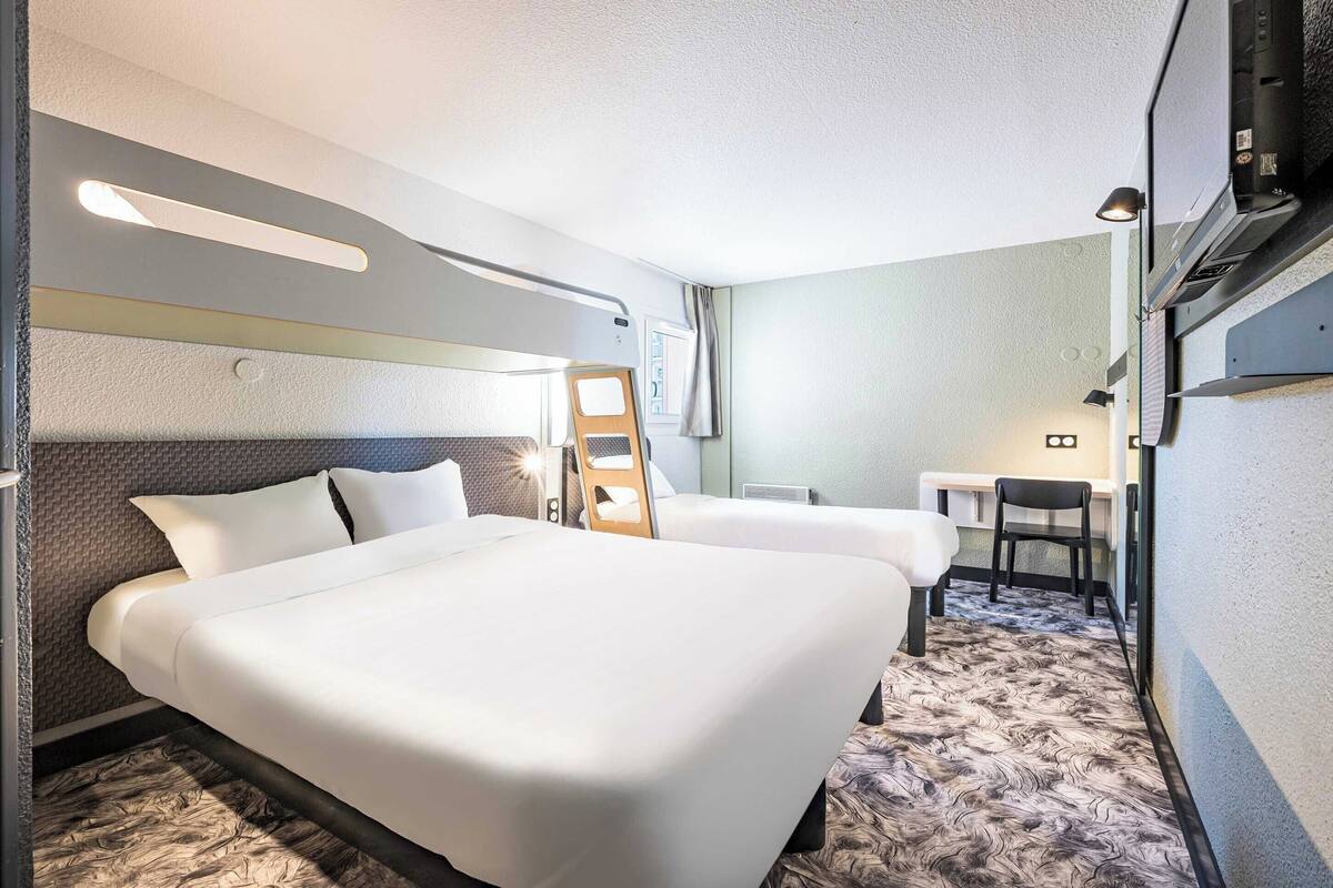 Una habitació d'hotel amb un llit gran, un escriptori, una cadira i una taula petita.