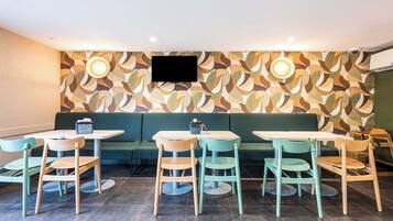 Ein Restaurant mit Wandverkleidung, grünen Sitzgelegenheiten und einem Flachbildfernseher.