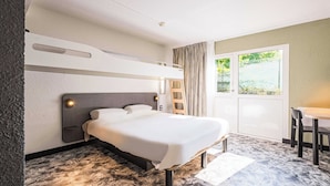 Una habitación de hotel moderna con una cama litera, un escritorio y vistas a zonas verdes.