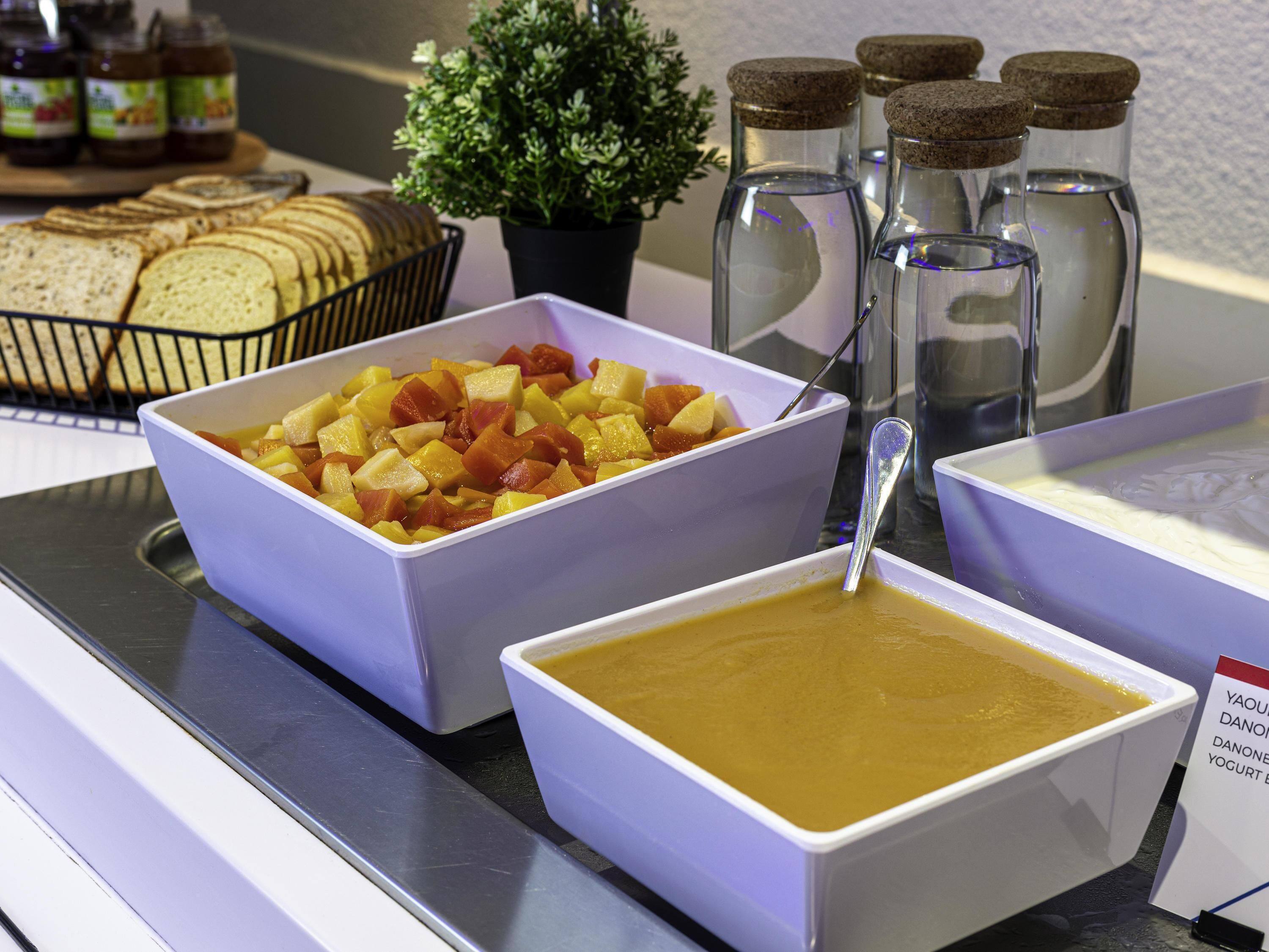 Ein Buffet mit Schalen voller Obst, einer Schale Suppe und Gläsern mit Soßen.