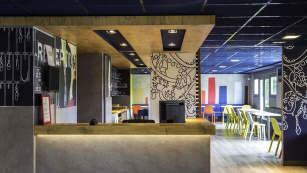 A modern office space with a reception desk, wooden ceiling, and colorful wall art.