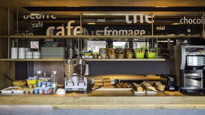 A café counter with a coffee machine, various food items, and a display of baked goods.
