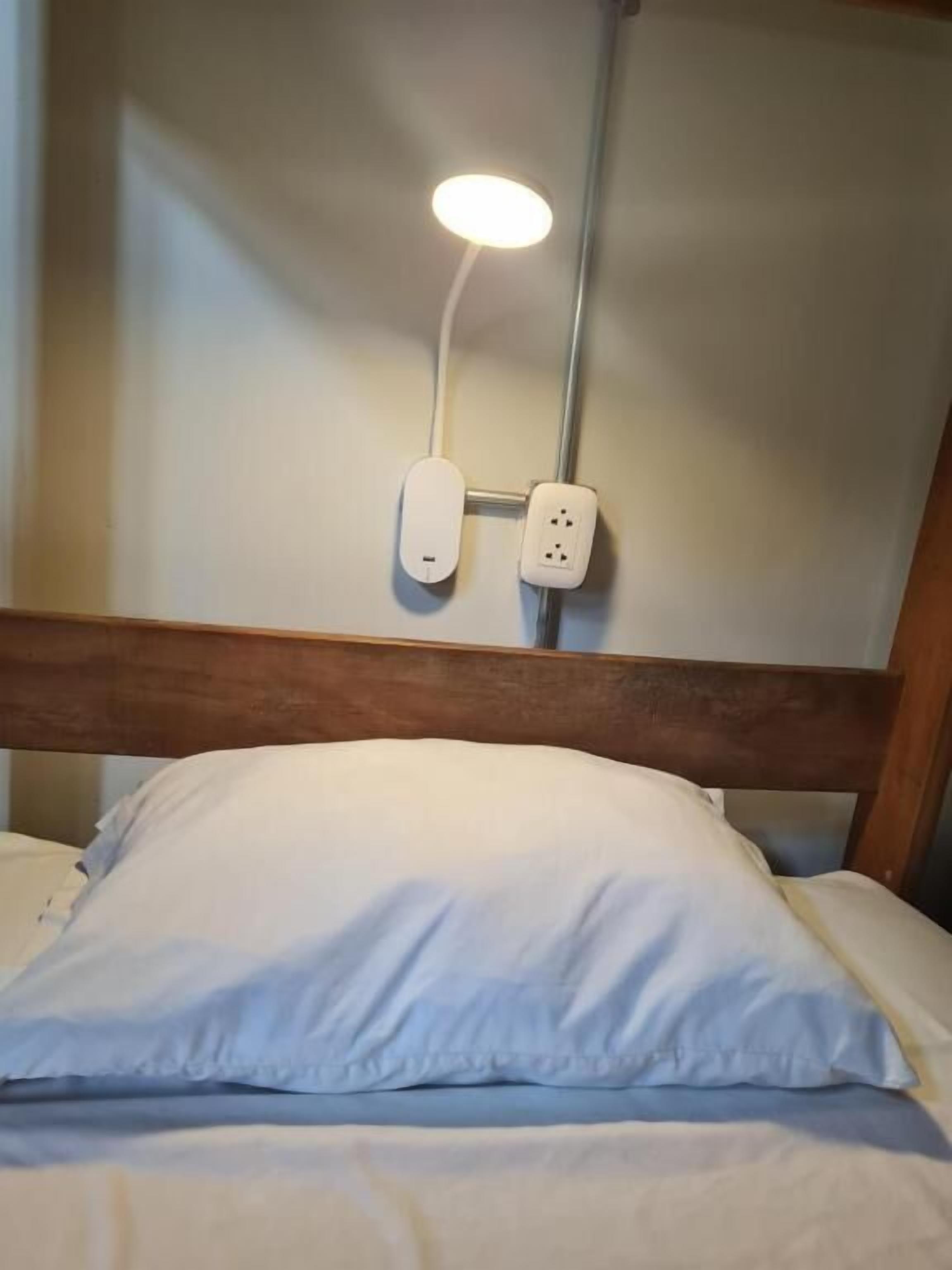 Una cama con un almohadón blanco y un cabecero.