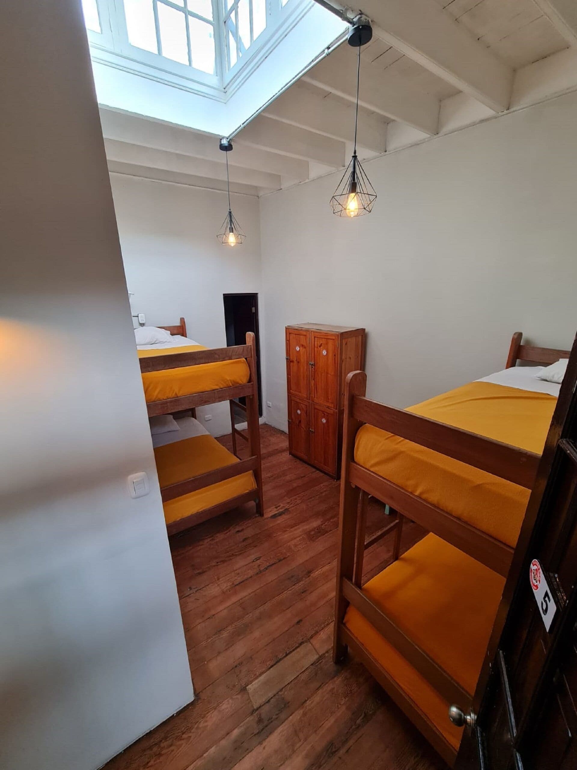 Ein Schlafsaalzimmer mit Etagenbetten, Holzschränken und einem Dachfenster.