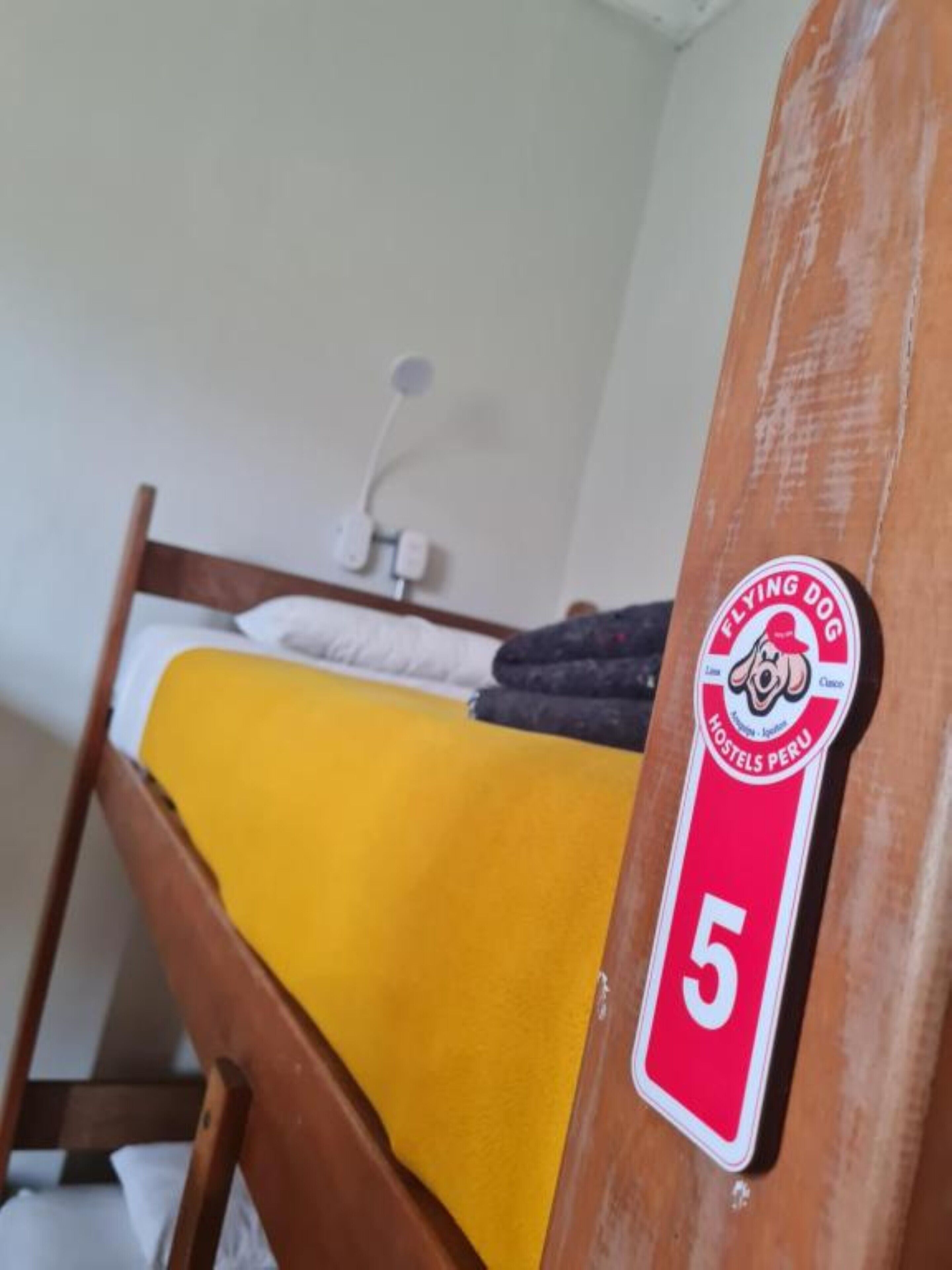A bunk bed with a yellow blanket and a sign indicating room number 5.