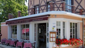 Een restaurant met terras en een bord waarop staat 'LE CHALET DE LA FORET RESTAURANT'.