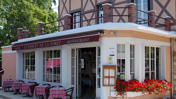 Een restaurant met terras en een bord waarop staat 'LE CHALET DE LA FORET RESTAURANT'.
