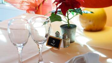 Une table avec deux verres à vin, une petite plante en pot, un ensemble de salière et de poivrière, et une serviette.