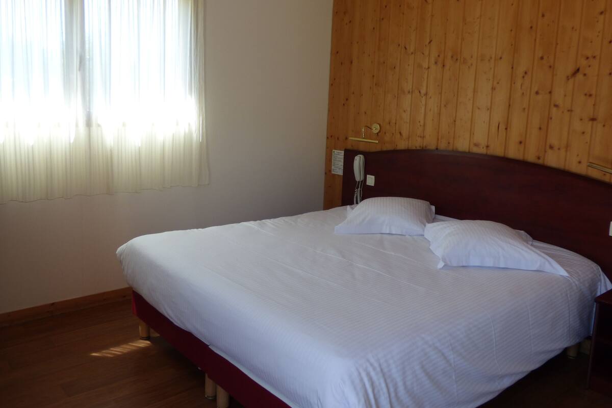 Un llit ben fet a una habitació amb panells de fusta a les parets i un sostre de fusta.
