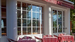 Een restaurant genaamd "Le Chalet de la Foret" met terras en grote ramen.