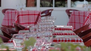 Een restaurant met gedekte tafels, herkenbaar aan rode en witte geruite tafelkleden en helder servies.