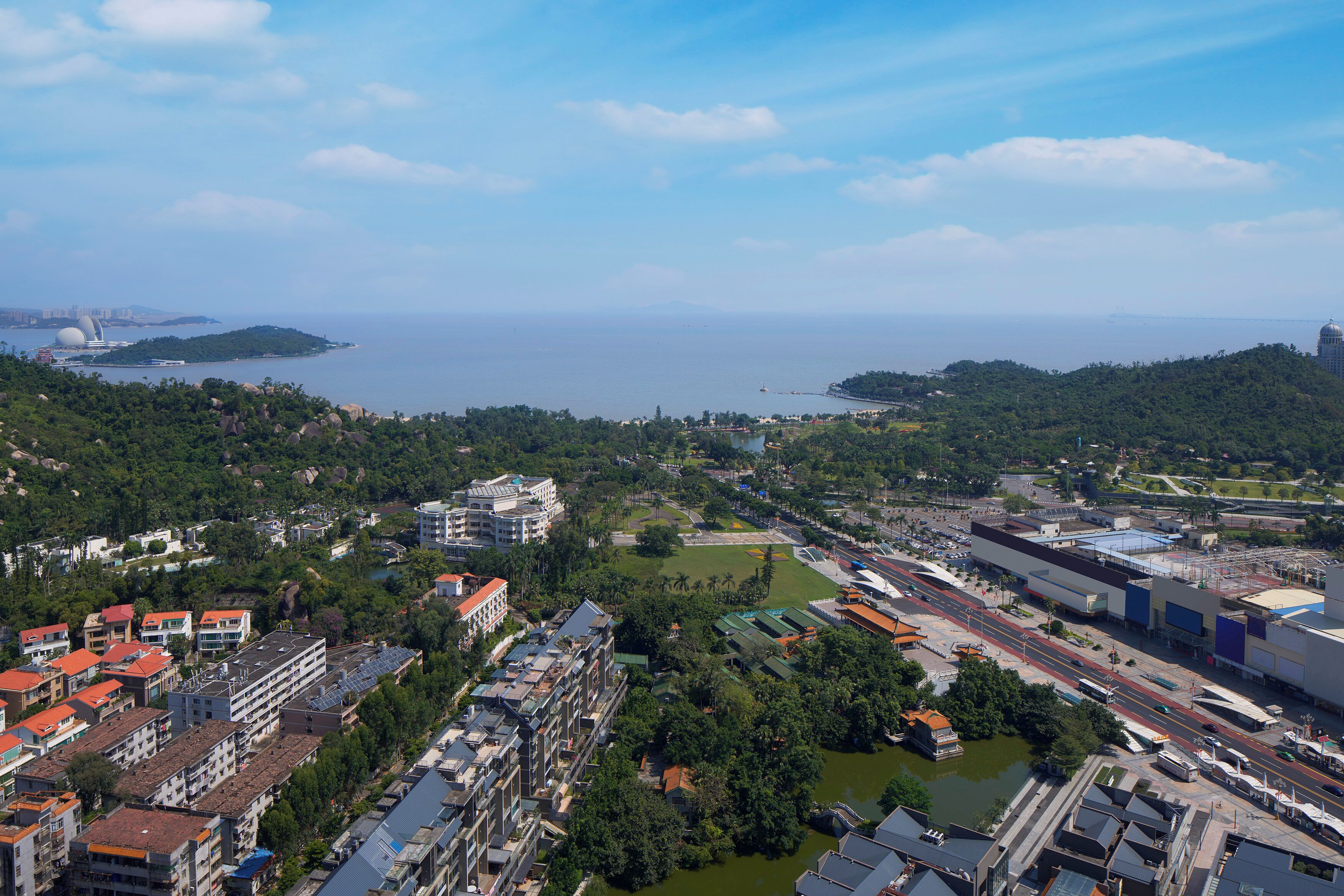 Vista aérea de una ciudad costera con densa construcción urbana, un río y una isla distante.