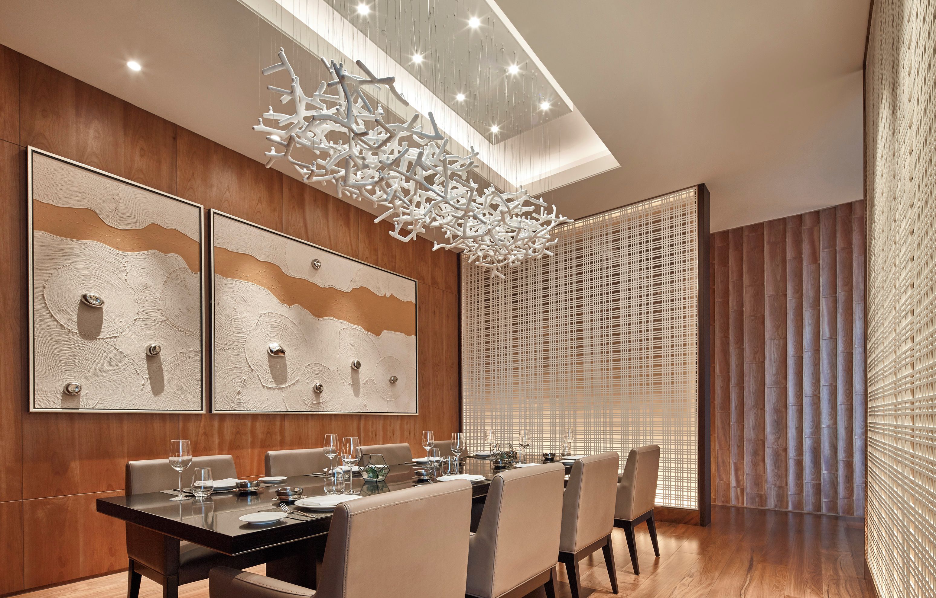 A modern dining room with a long table, multiple chairs, and abstract wall art.
