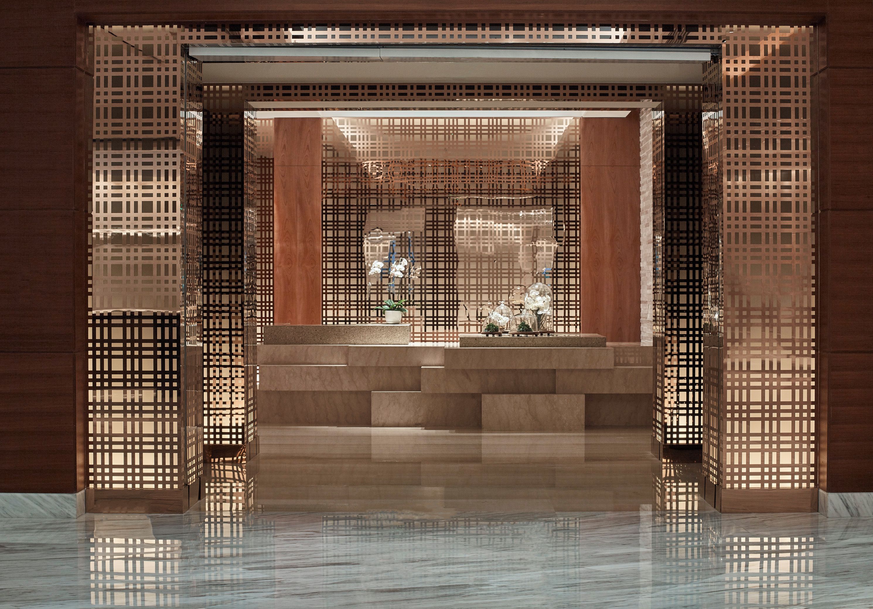 A modern interior with a glass entrance, a staircase, and decorative elements like plants and glassware.