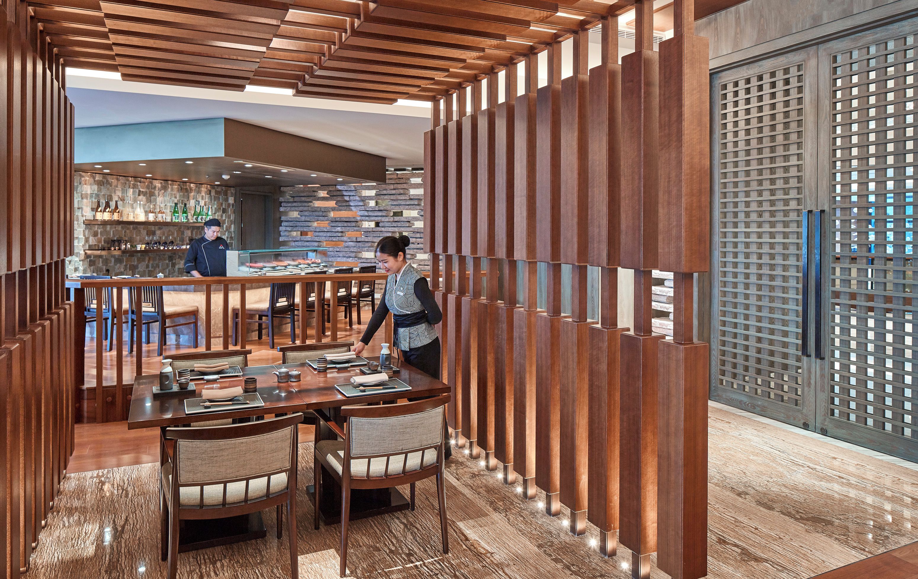 A restaurant with wooden partitions, a bar area, and a seating arrangement with tables and chairs.
