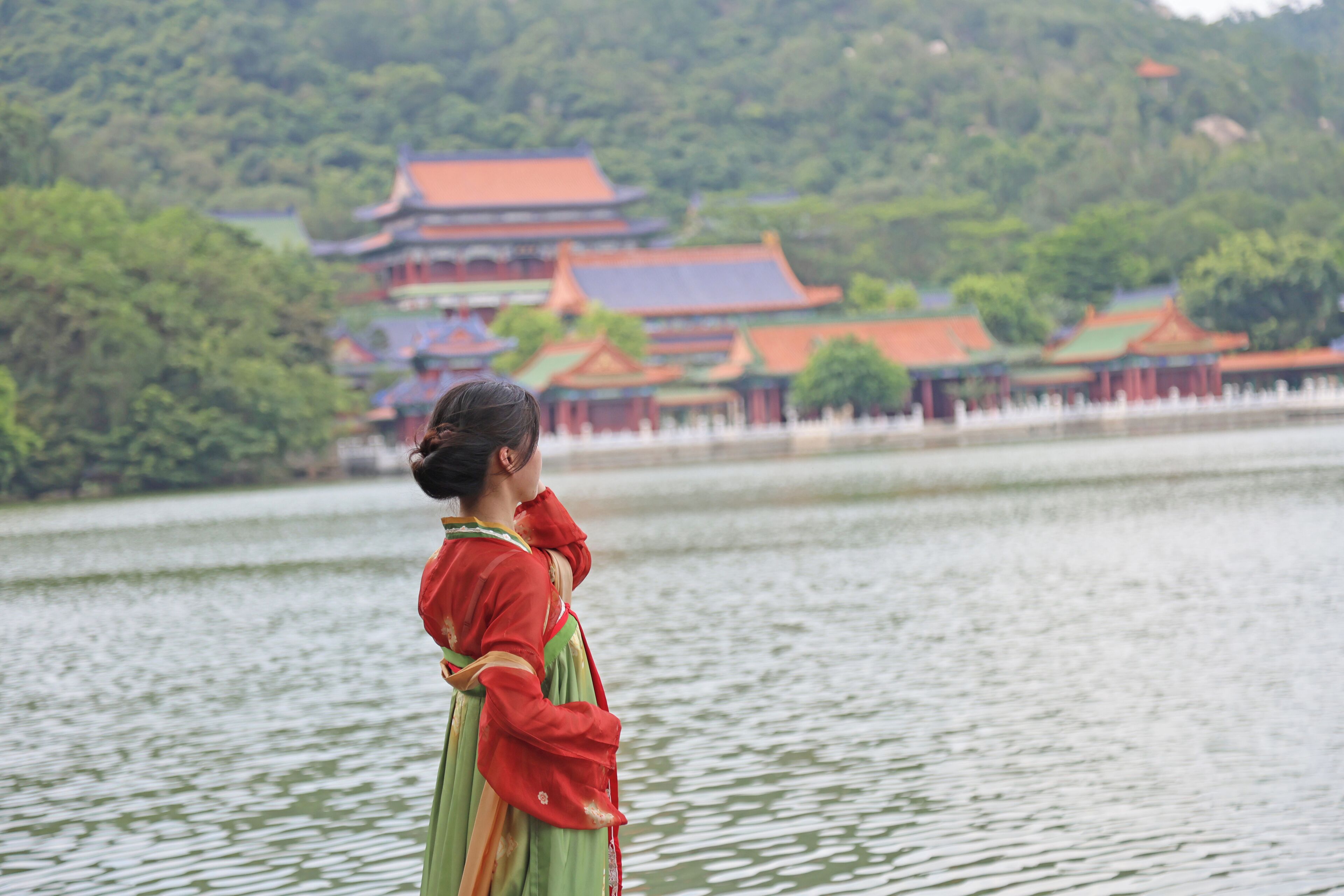 A traditional building with multiple roofs and a body of water in the foreground.