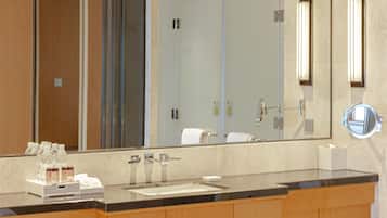 A modern bathroom with a large mirror, a bathtub, and a sink.