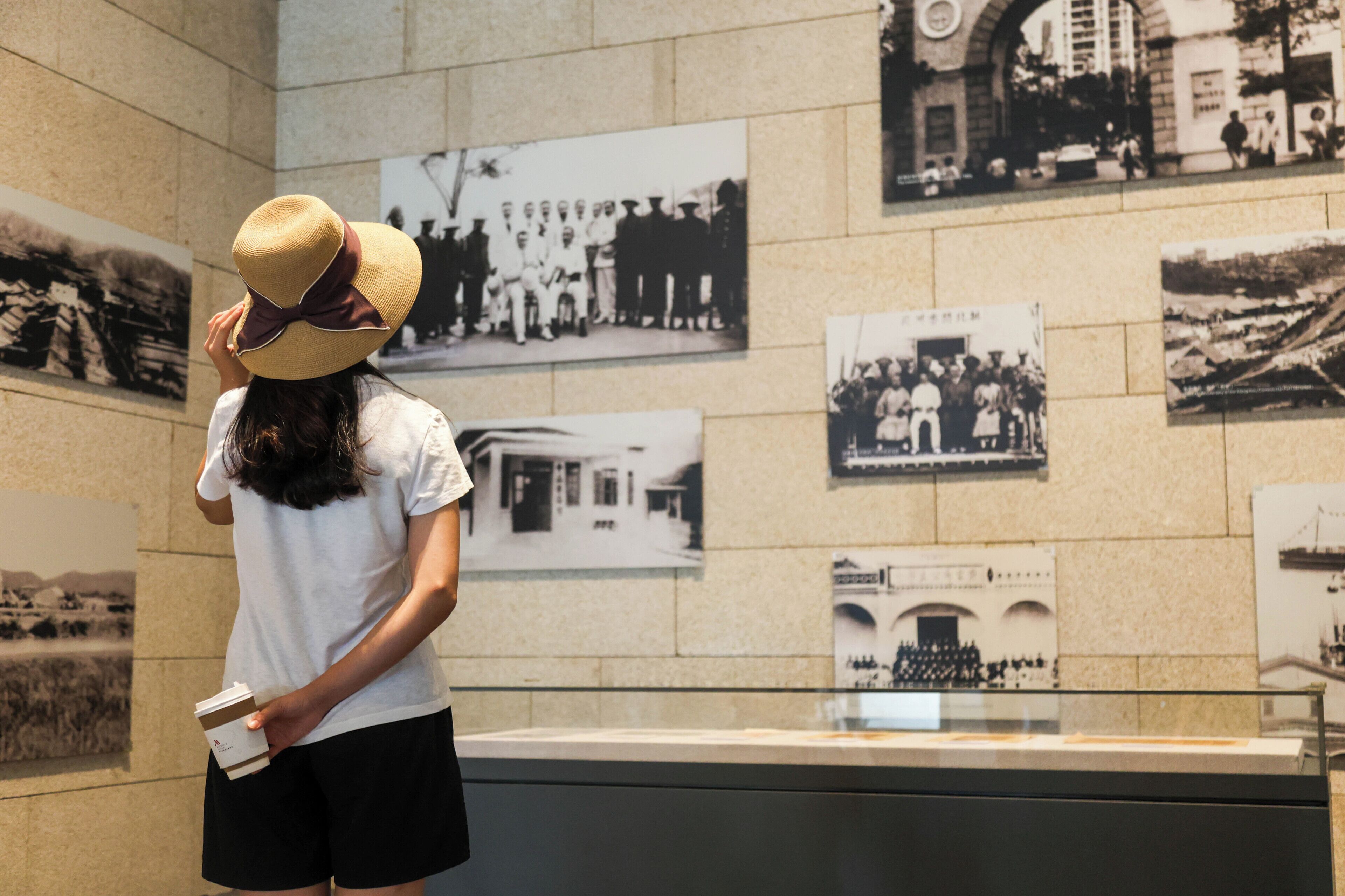 Eine Person steht vor einer Wand mit historischen Fotos.