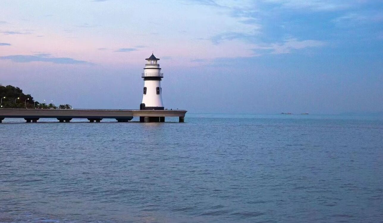 Un phare se dresse sur une jetée qui s’avance dans des eaux calmes.