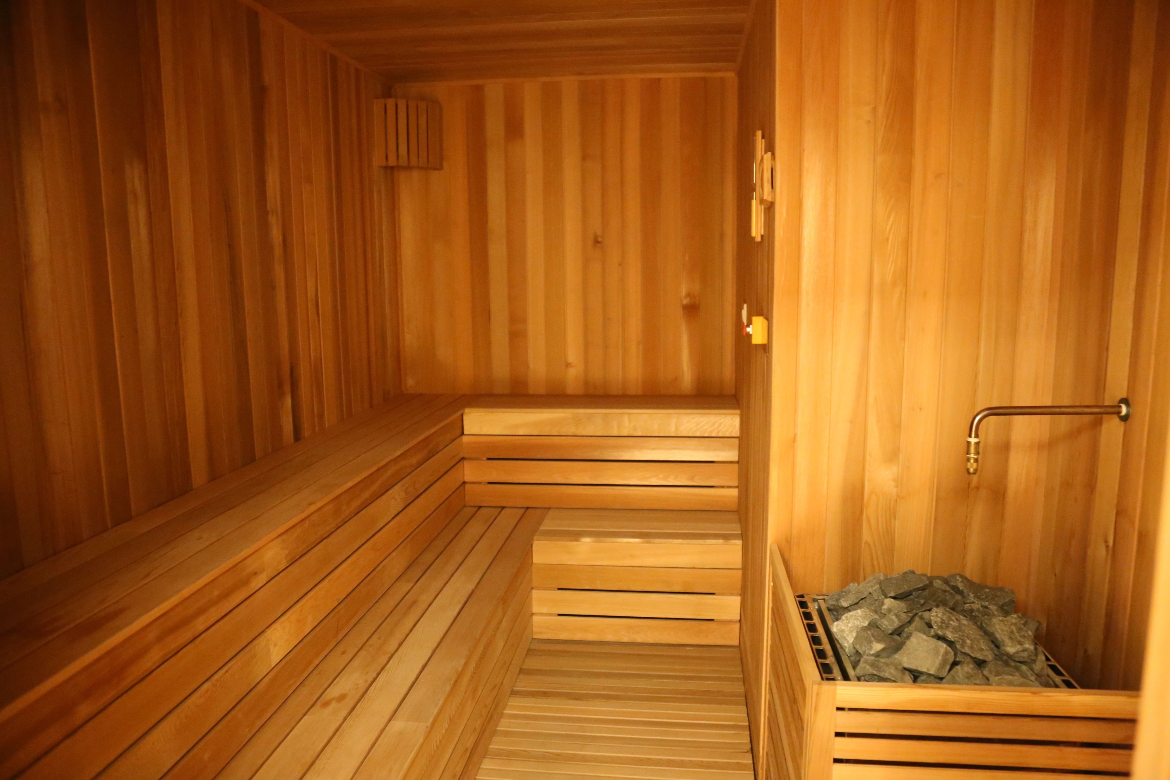 A wooden sauna with benches and a stone-filled container.