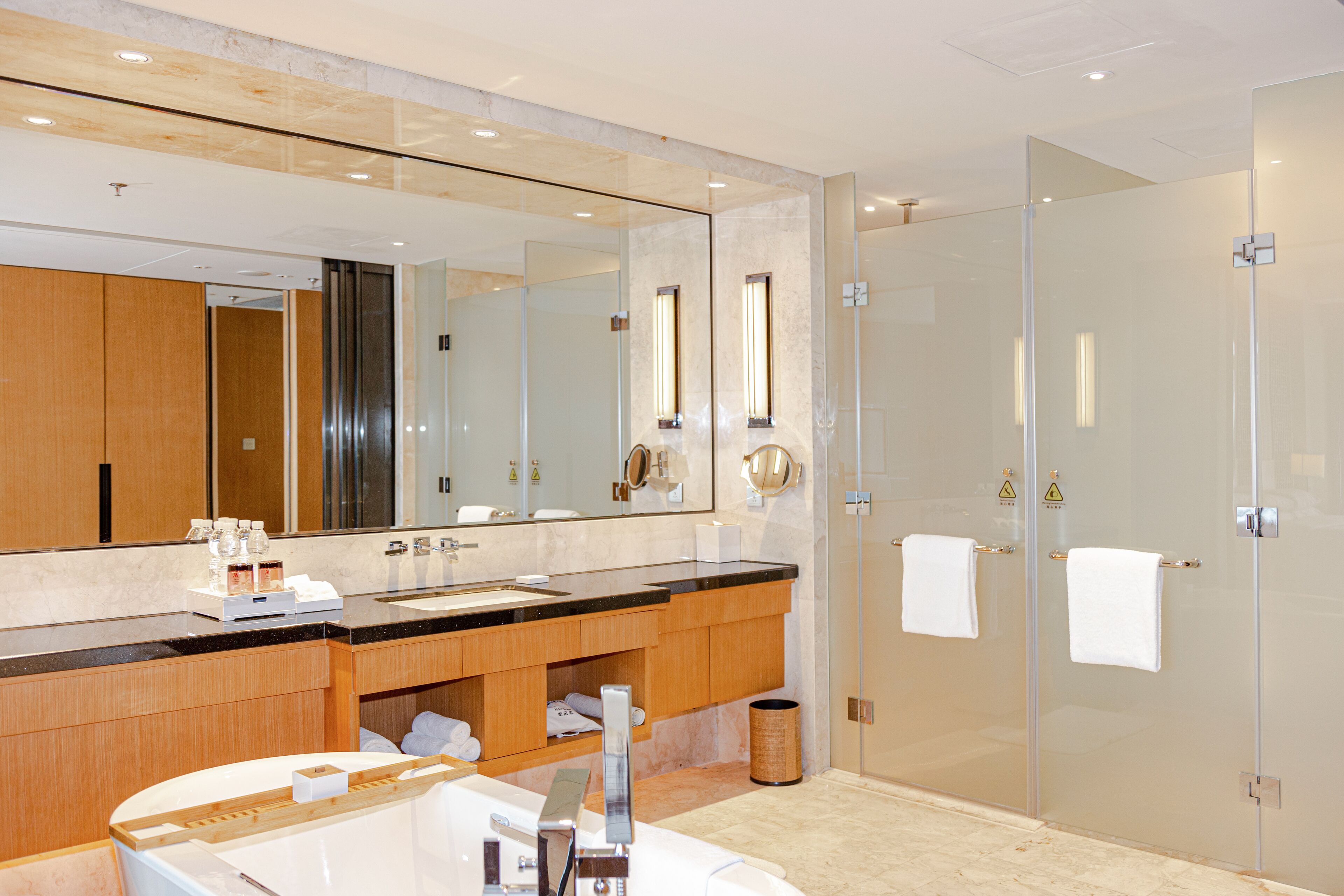 A modern bathroom with a large mirror, a bathtub, a sink, and a glass shower enclosure.