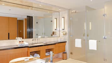 A modern bathroom with a large mirror, a bathtub, a sink, and a glass shower enclosure.