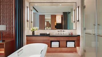 A modern bathroom with a large mirror, a bathtub, a vanity with a sink, and a glass shower enclosure.