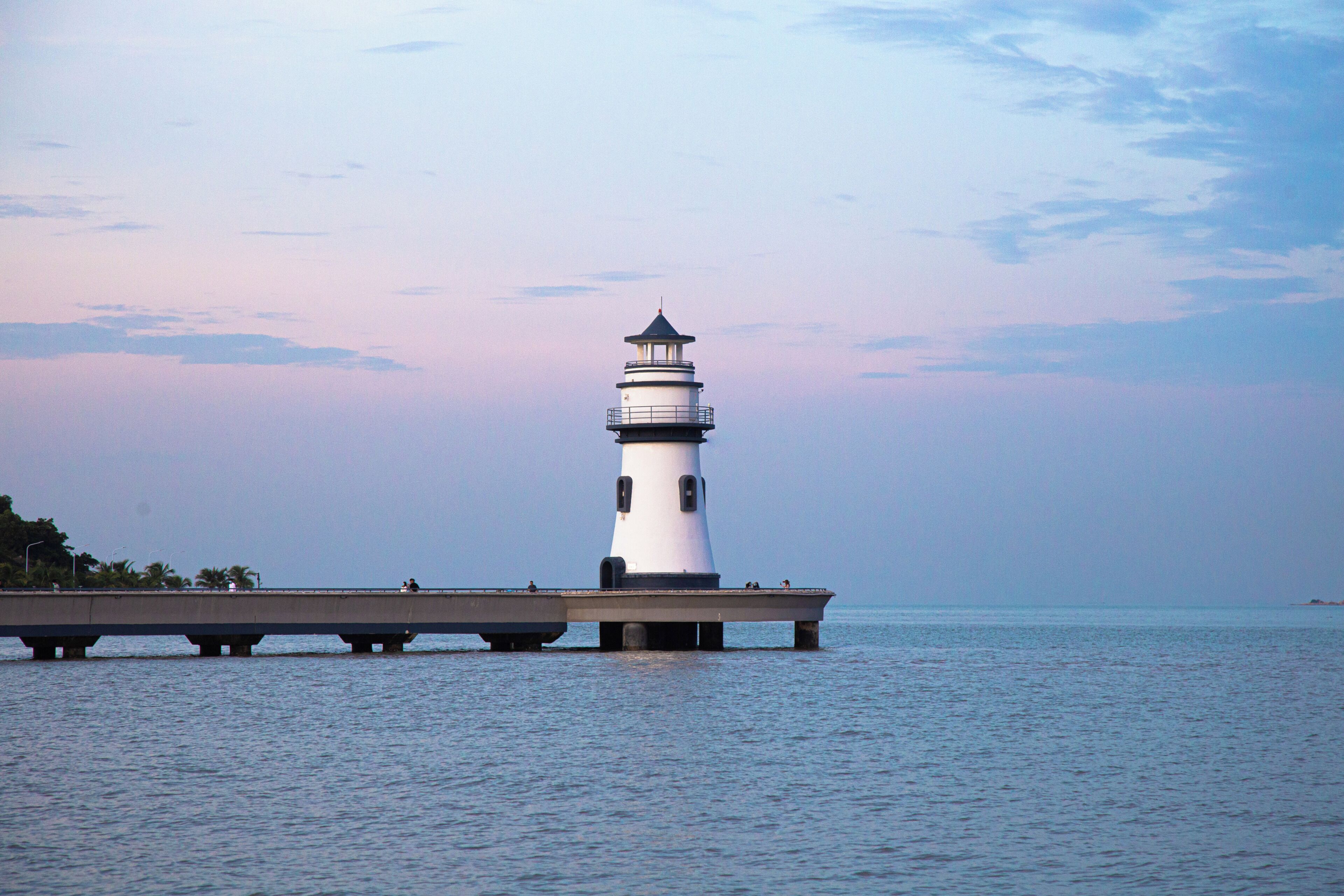 Un faro su un molo che si protende in acque calme.