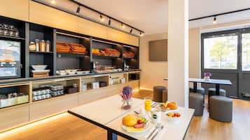 Ein modernes Frühstücksbuffet mit Sitzgelegenheiten und großen Fenstern.