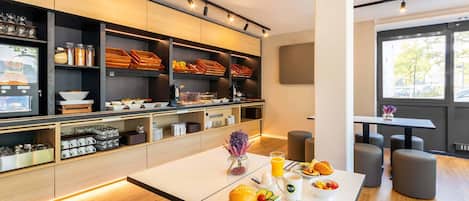A modern breakfast setup with a buffet, seating area, and large windows.