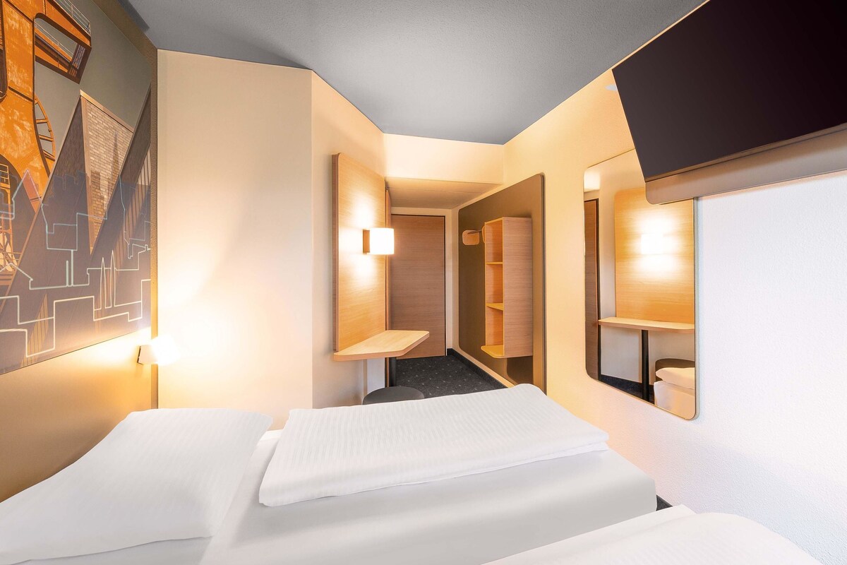 Een hotelkamer met twee bedden, een gang en een badkamer.