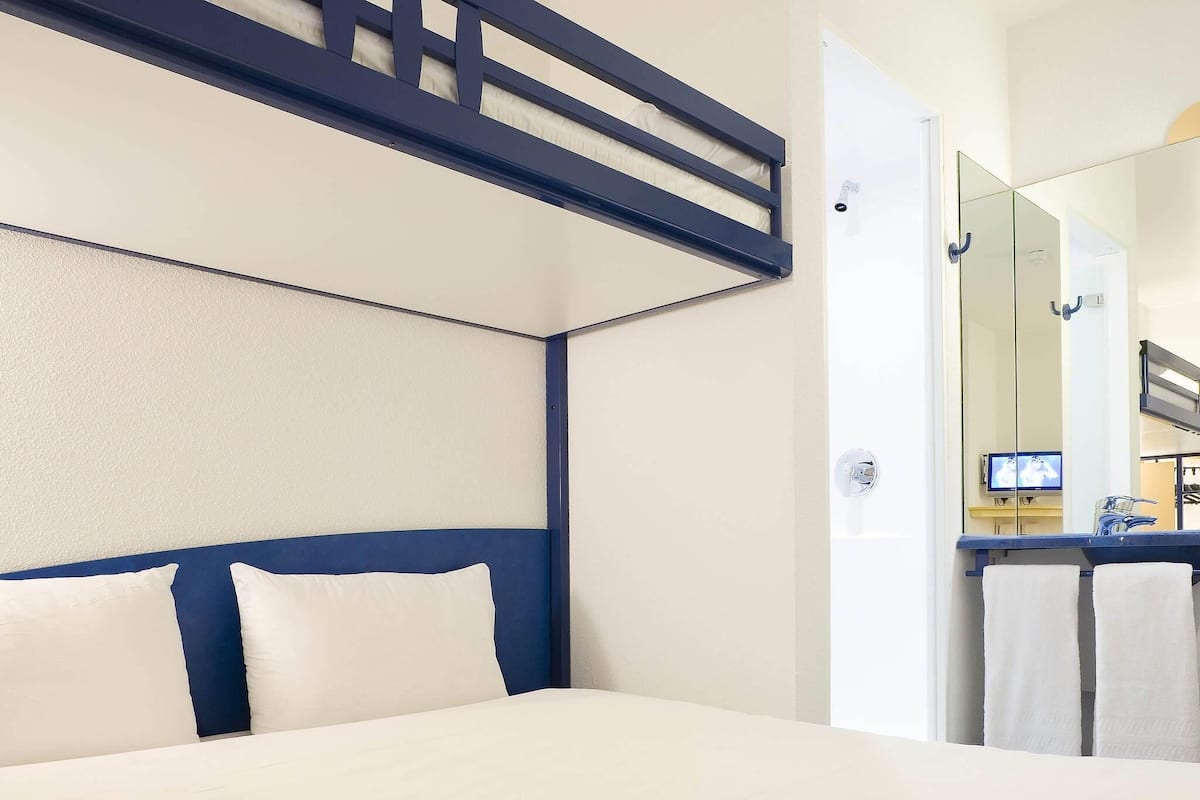 A hotel room with a bed, a mirror, and a bathroom visible through an open door.