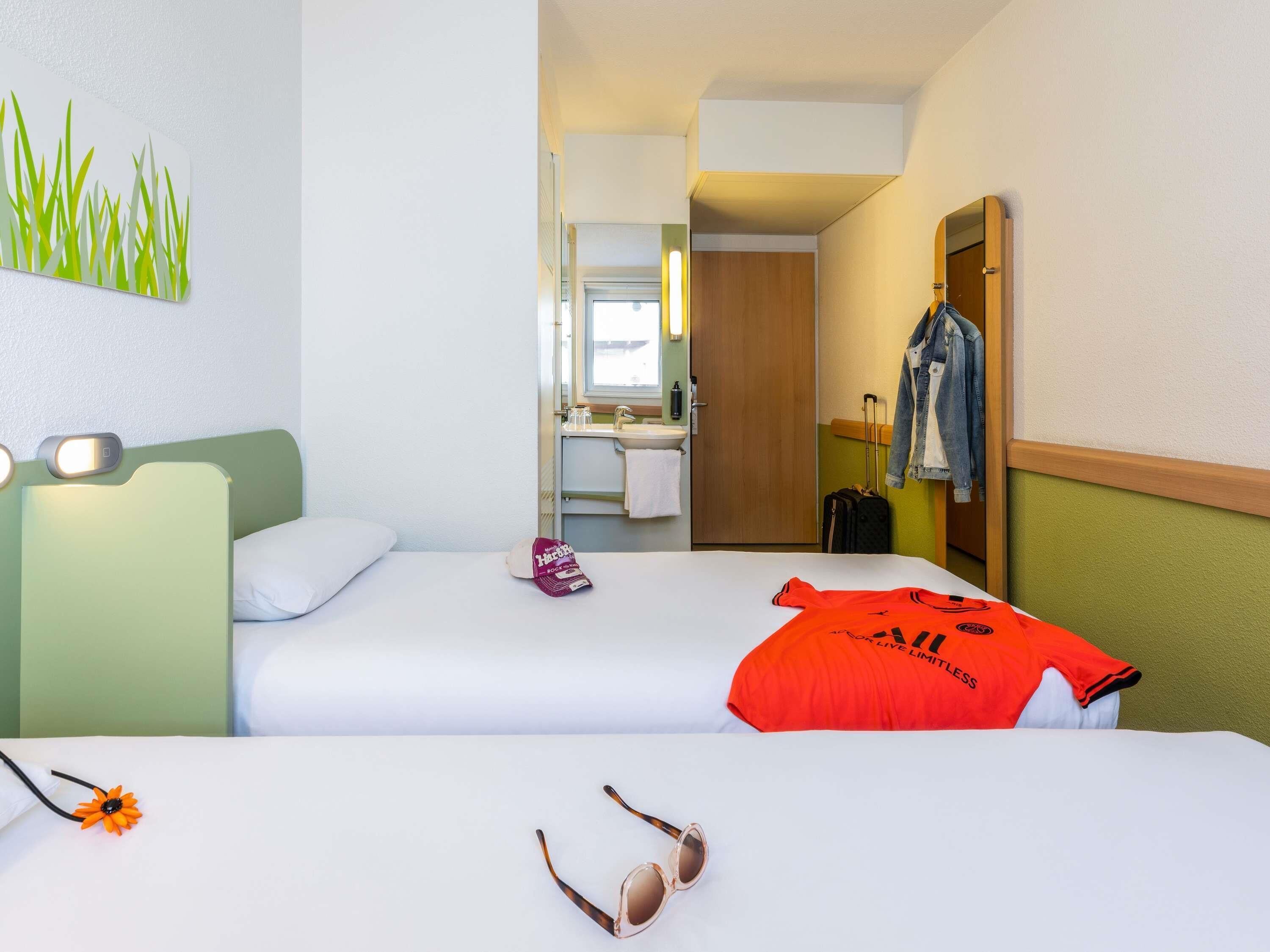 Une chambre d’hôtel avec deux lits, une salle de bain et une vue sur l’extérieur.