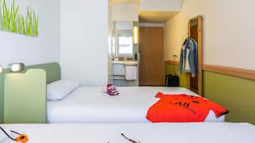 A hotel room with two beds, a bathroom, and a view of the outside.
